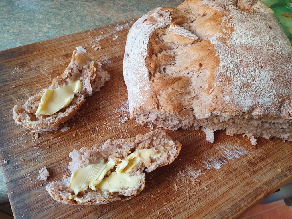 hazelnut bread on a wood board, with two slices buttered
