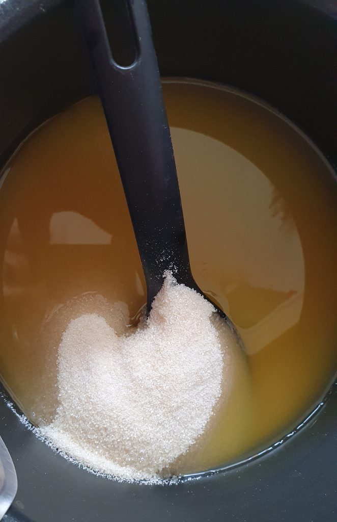 sugar in the pan of yellow liquid, some in the liquid some still dry above