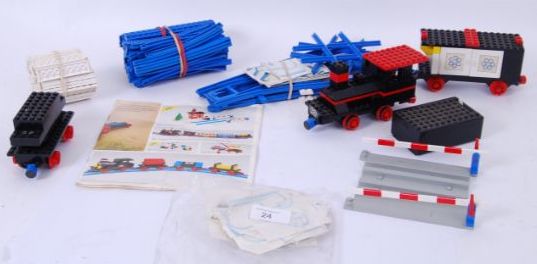 various train components on a table, with a railway crossing, many pack of blue tracks some instructions and wagons