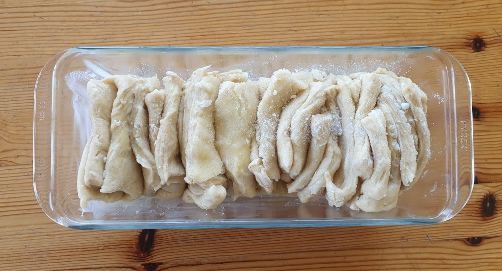 the rectangles of dough at piled up horizontally in the cake tin 