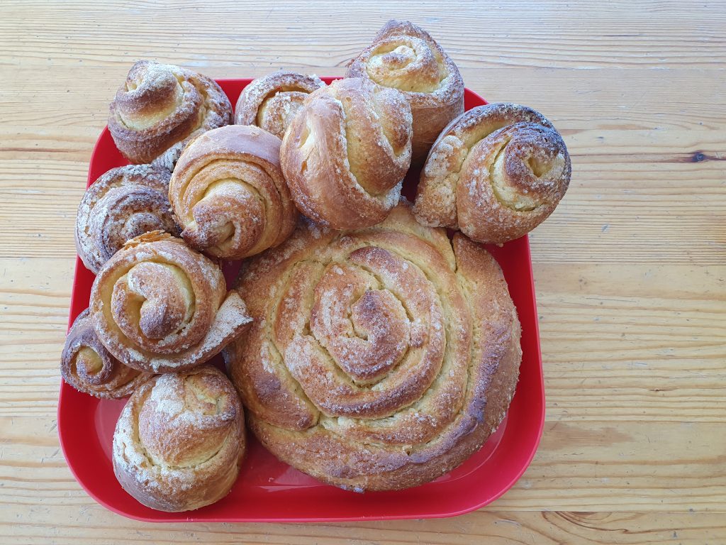 10 little spirales of brioches and a wider one but more flat on a red tray  on a wood table