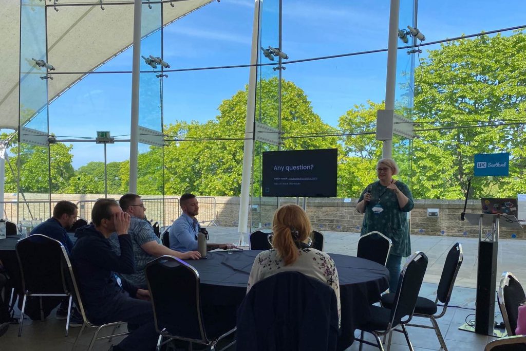 Me, standing with a mic, answering questions in front of the audience. In the back, it's glass walls showing big trees and a very blue sky