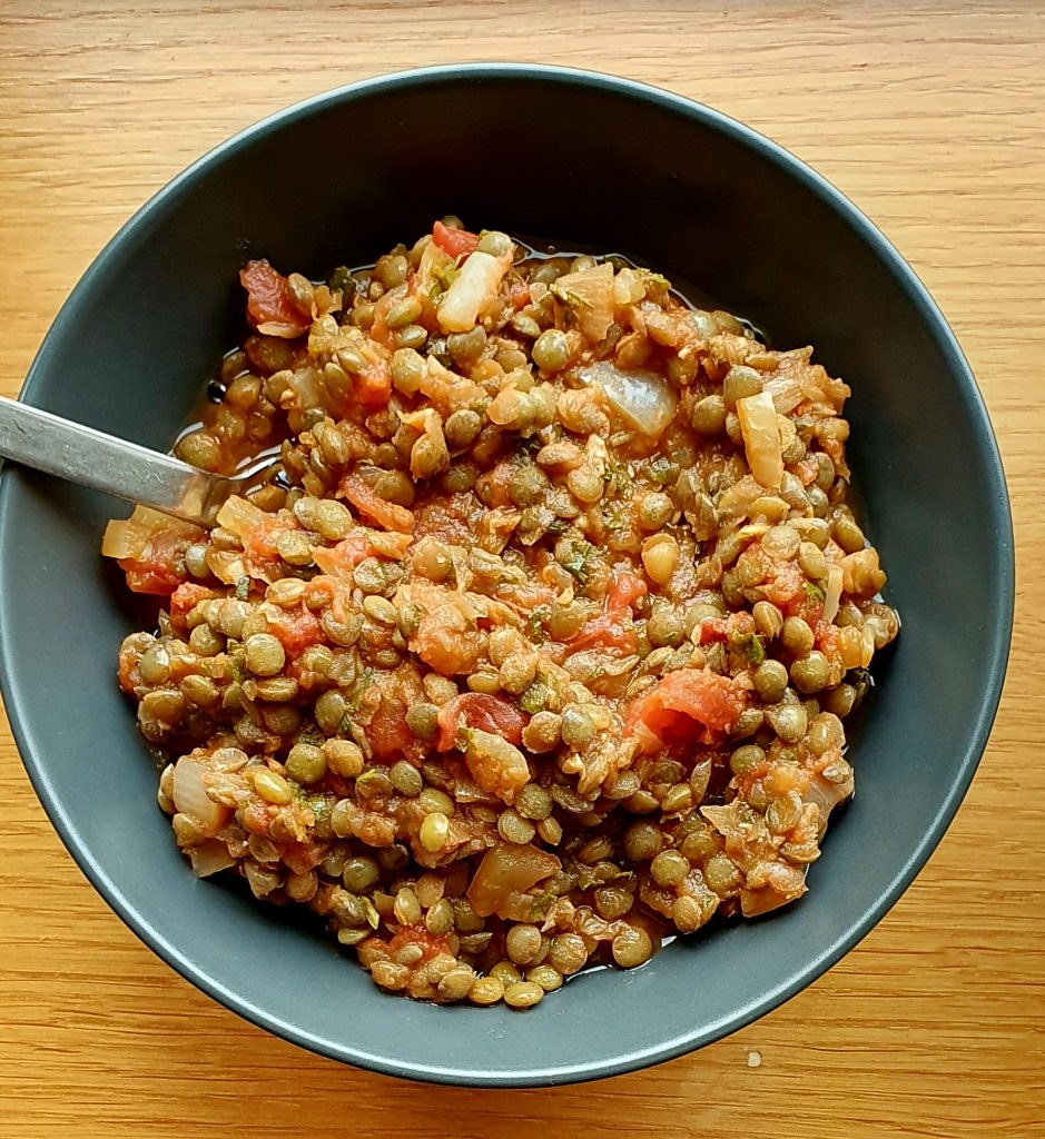 bowl of lentils with pieces of onions and tomatoes visible